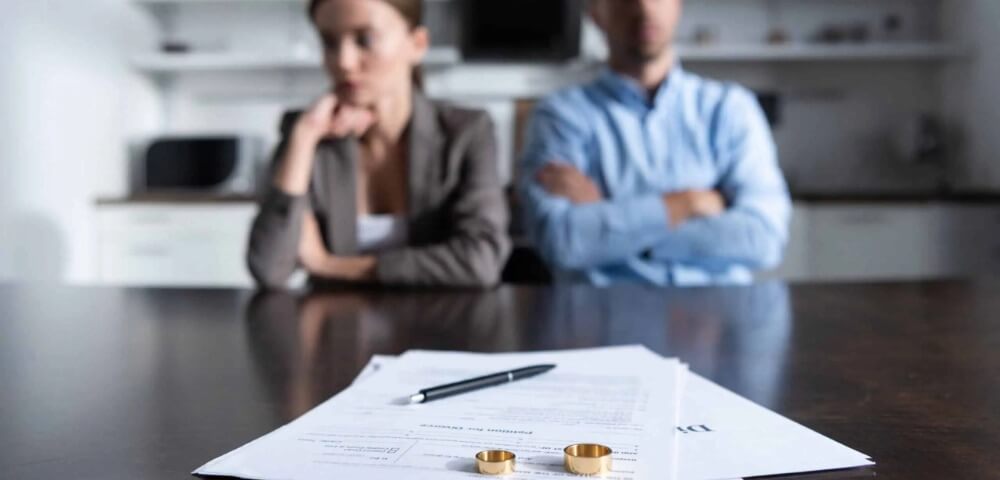 selective focus of couple sitting at table with divorce documents